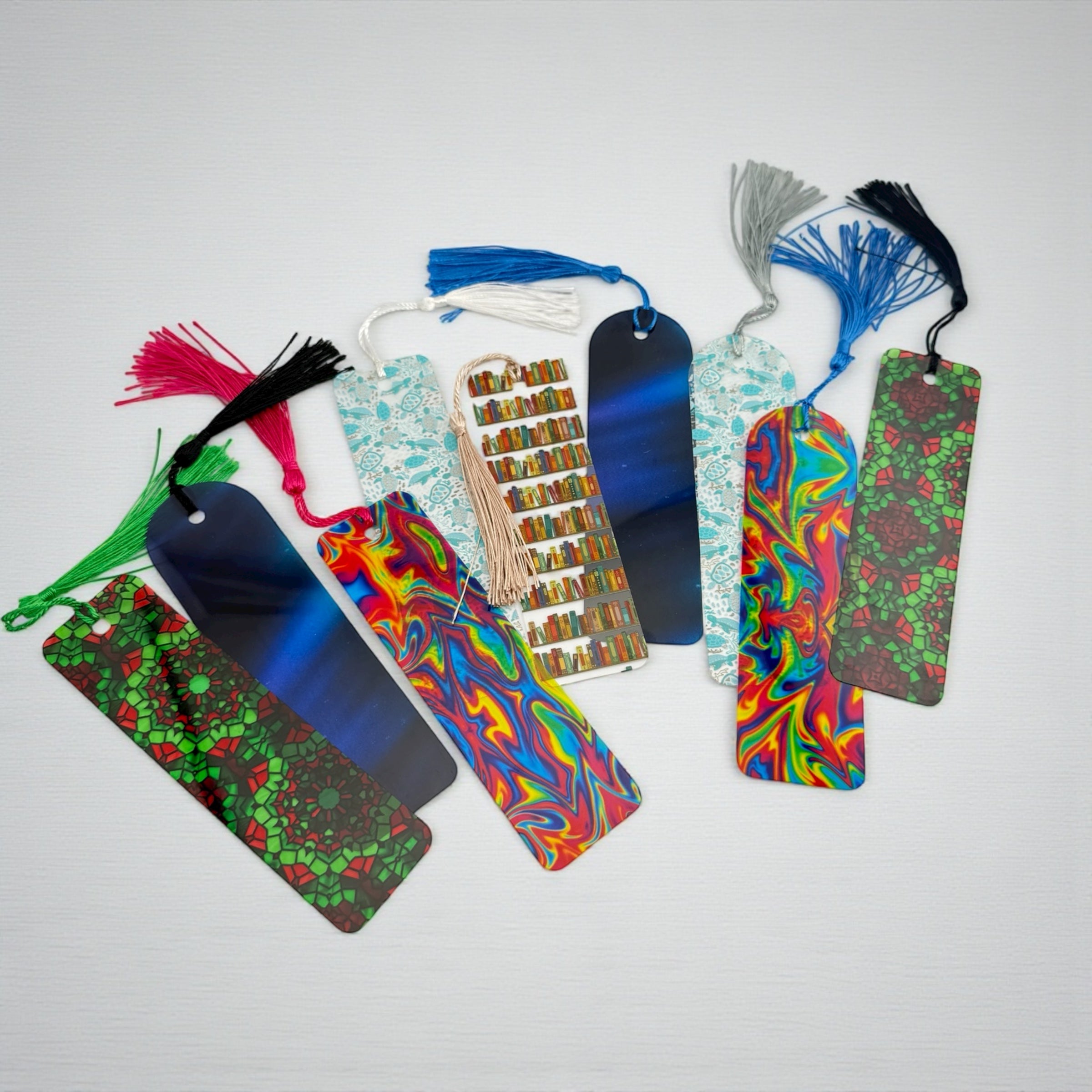 A collection of colorful, patterned bookmarks with tassels, arranged on a white background.