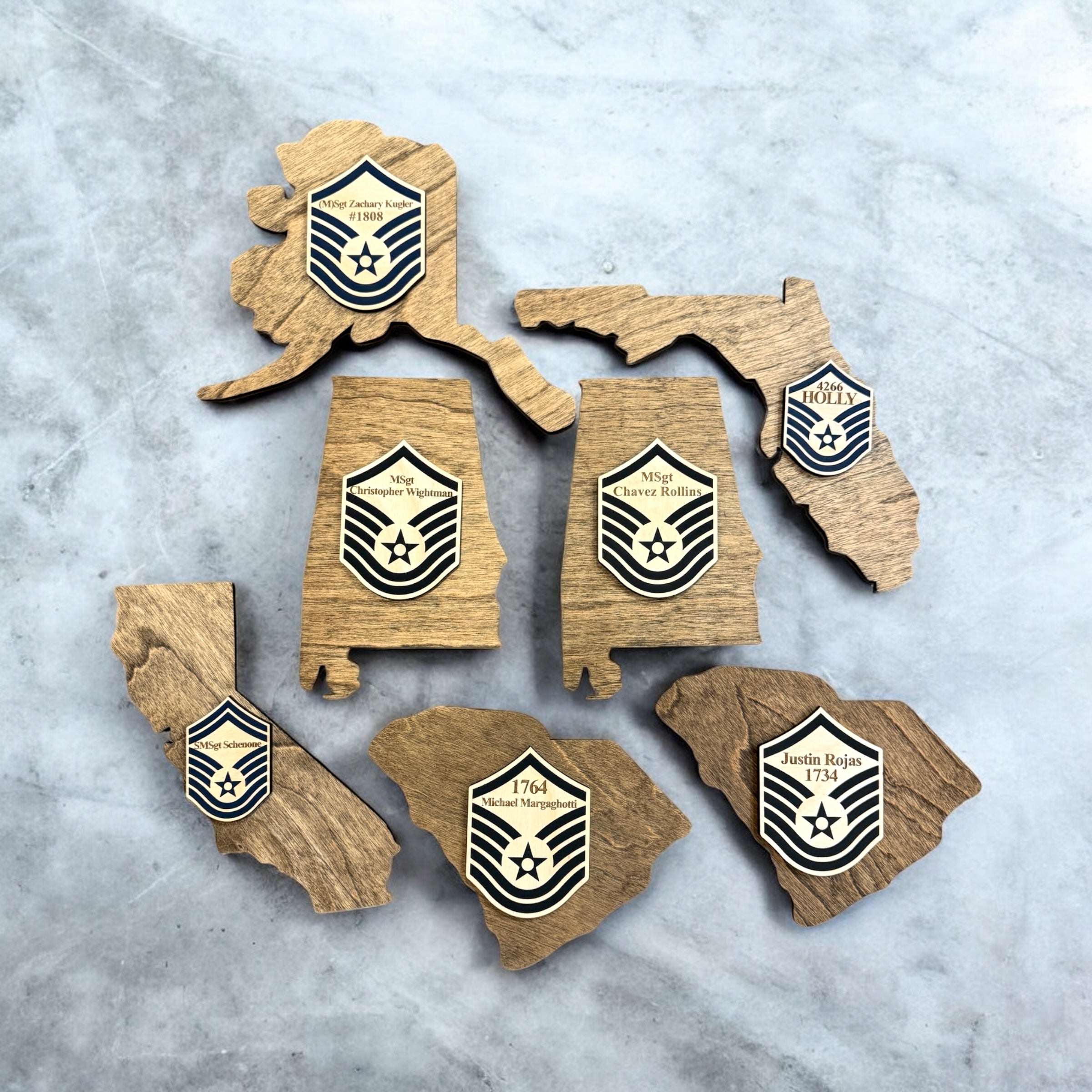 Wooden cutouts of U.S. states with military insignia on a textured surface