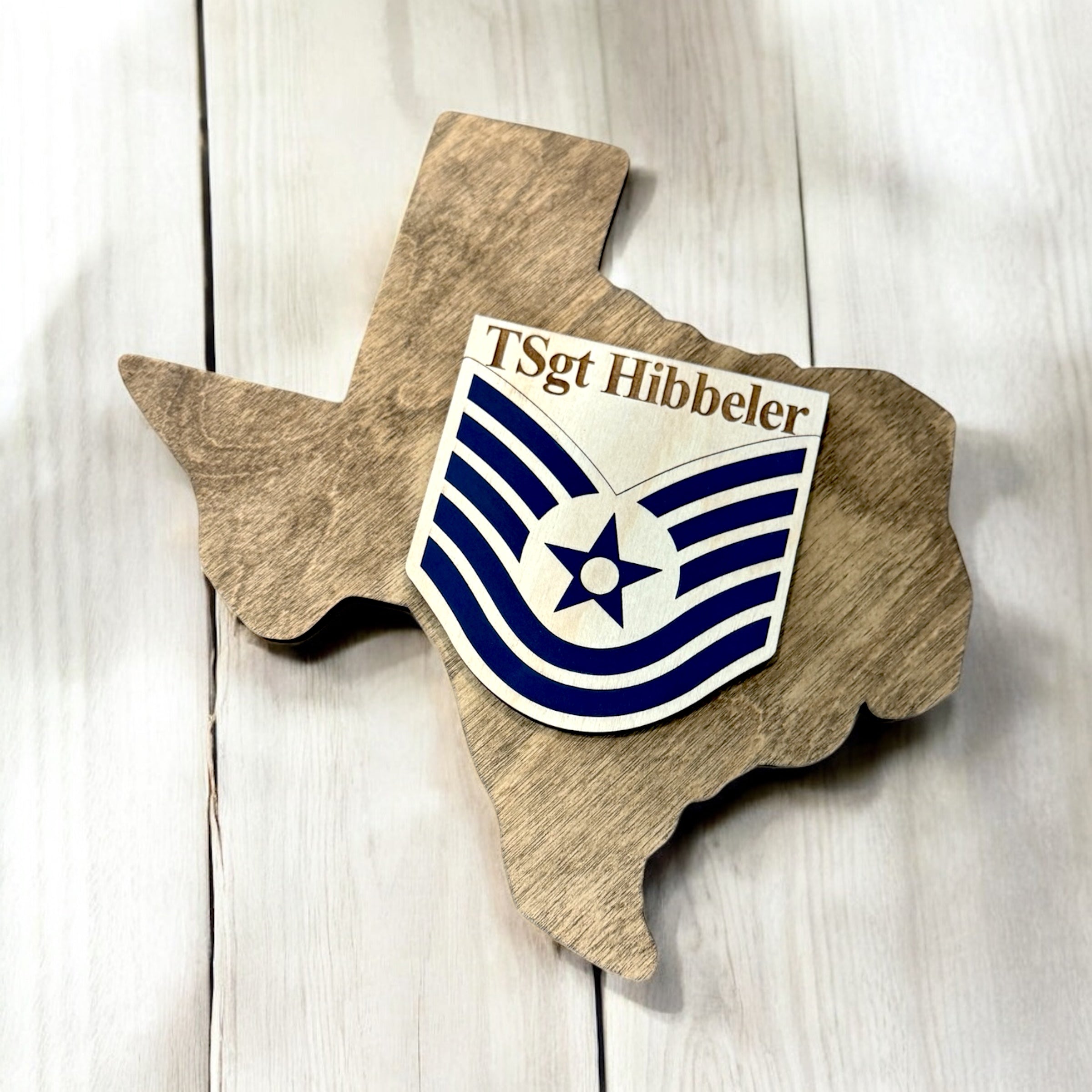 Wooden Texas-shaped plaque with a military insignia and 'T Sgt Hibbeler' text on a wooden background.