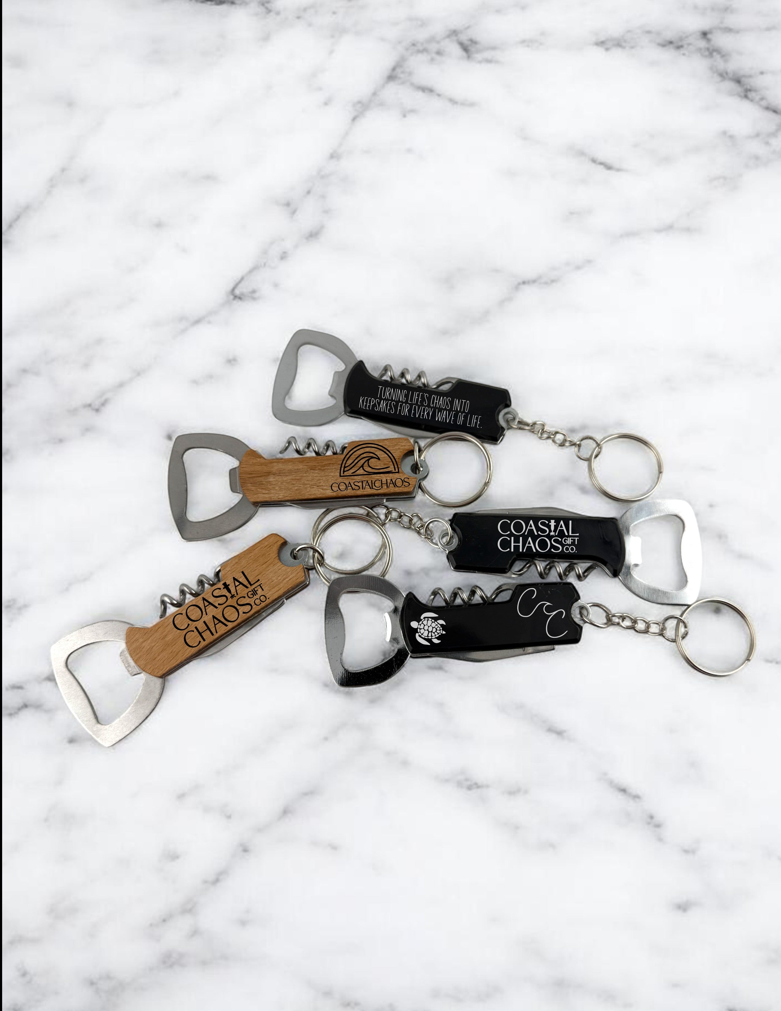 Coastal Chaos Co. multi-tool keychains with corkscrew and bottle opener. Wood and black finishes with engraved logos.