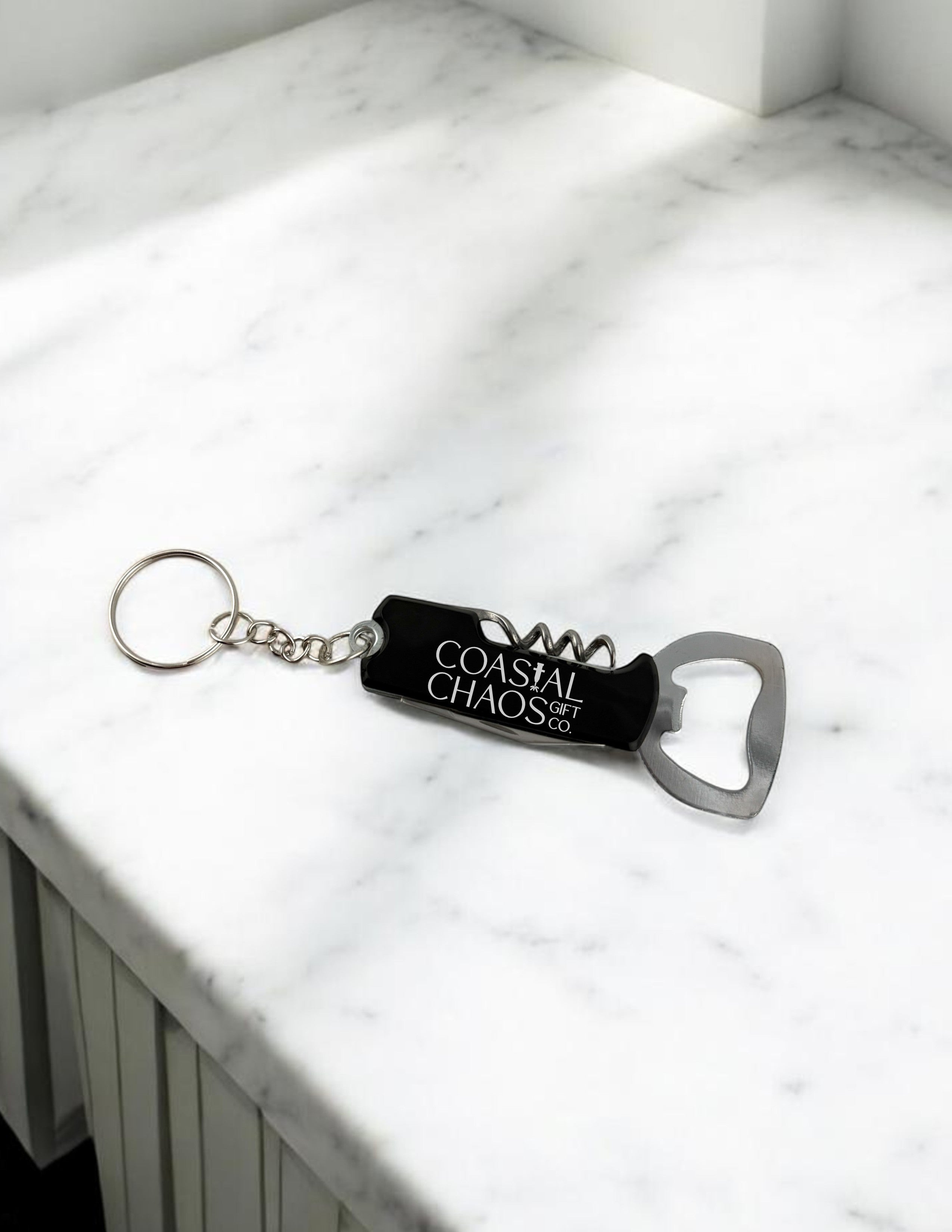 Coastal Chaos Co. black metal multi-tool keychain with corkscrew and bottle opener, engraved logo.