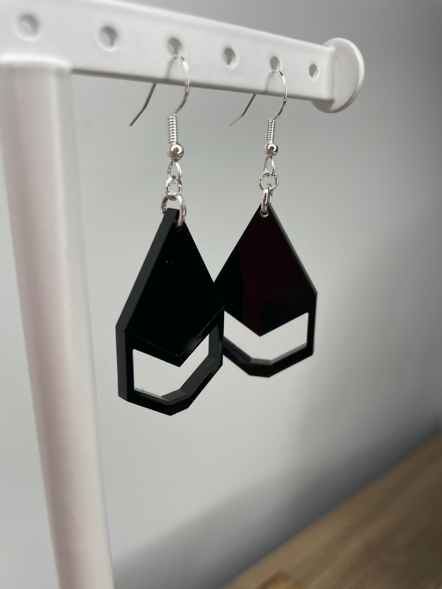 A pair of black geometric earrings with a triangular shape and a small cutout in the center.