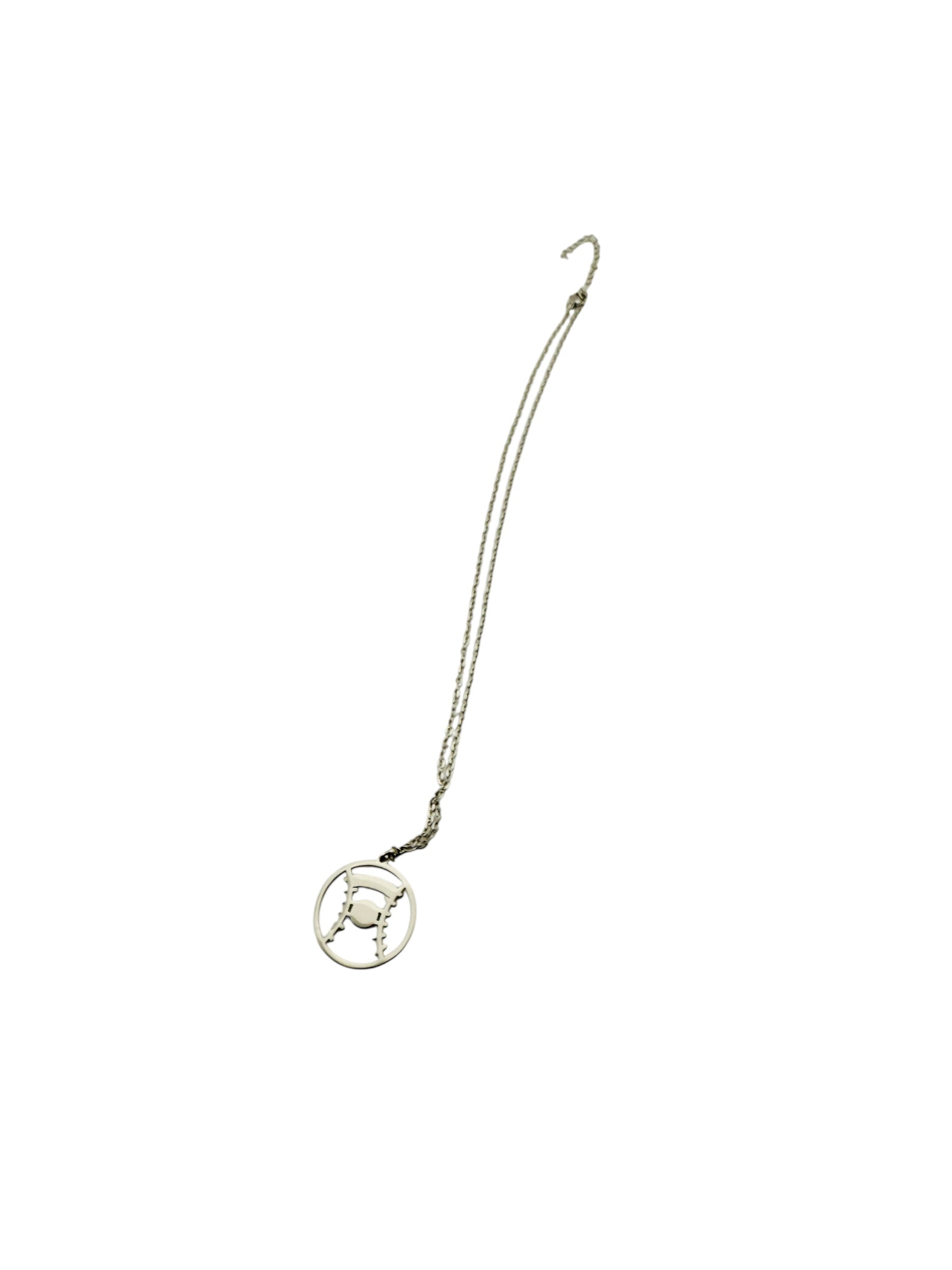 A silver necklace with a circular pendant featuring a design resembling a baseball or a similar sports ball.