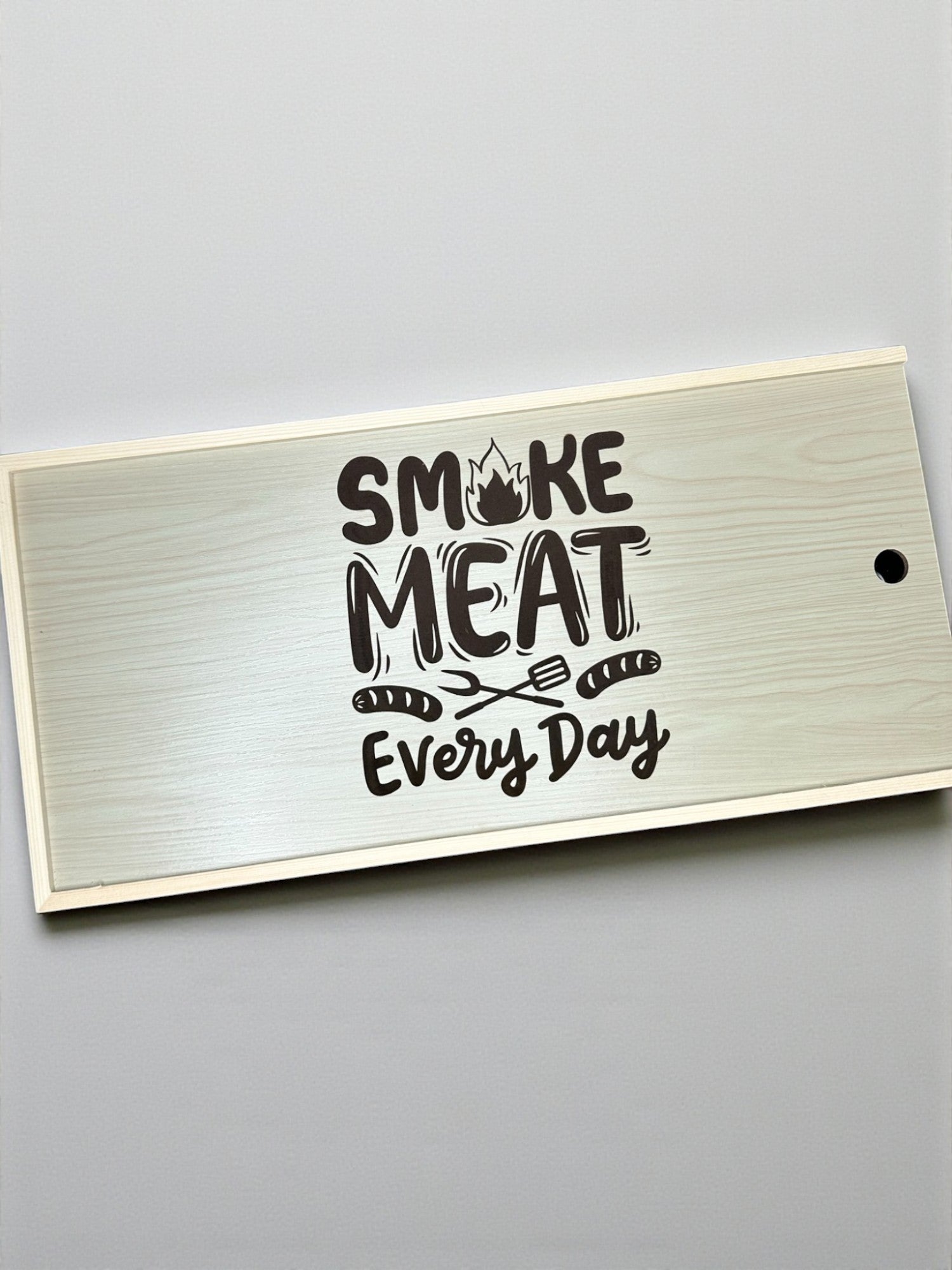 a wooden surface with the text "SMOKING MEAT EVERY DAY" printed on it.