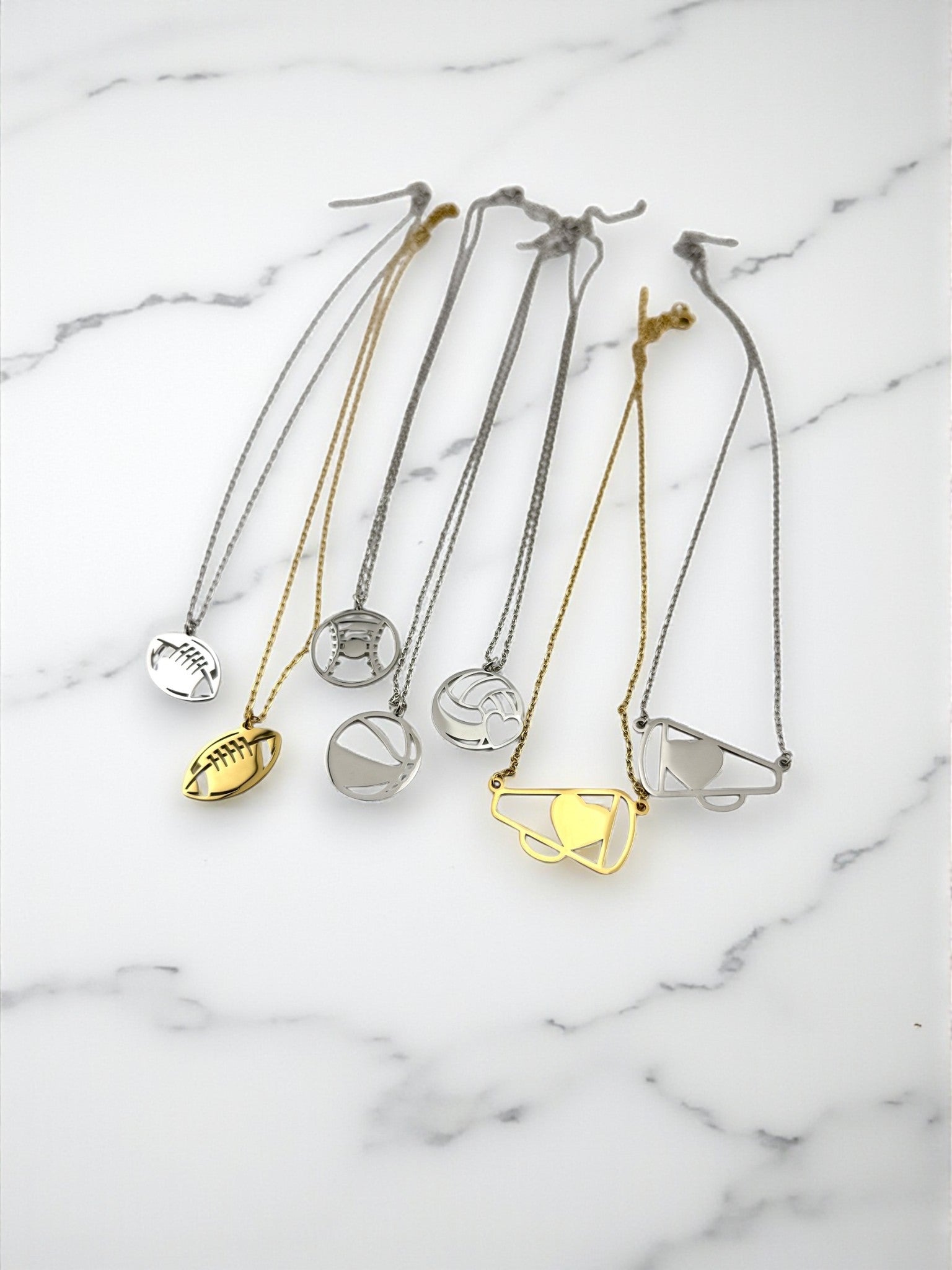 a collection of various necklaces and pendants, each featuring different designs and shapes, arranged on a marble surface.