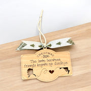 A wooden ornament with a ribbon and a message about the love between friends, hanging on a wooden surface.