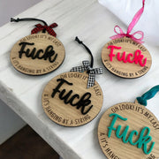 a collection of wooden ornaments with the word "FUCK" written on them, each with a different color ribbon.