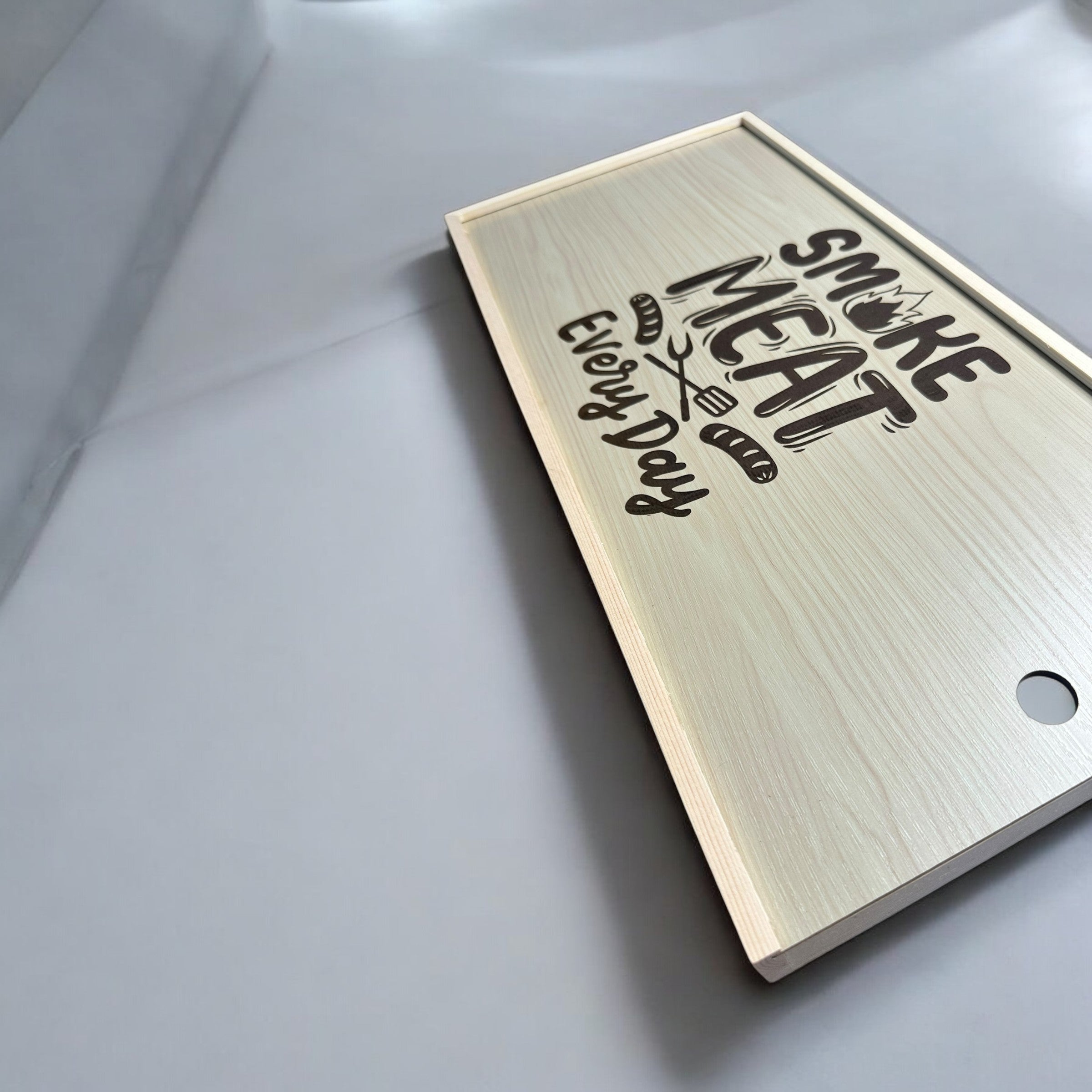 A wooden cutting board with the text "Smoke Meat Every Day" printed on it.