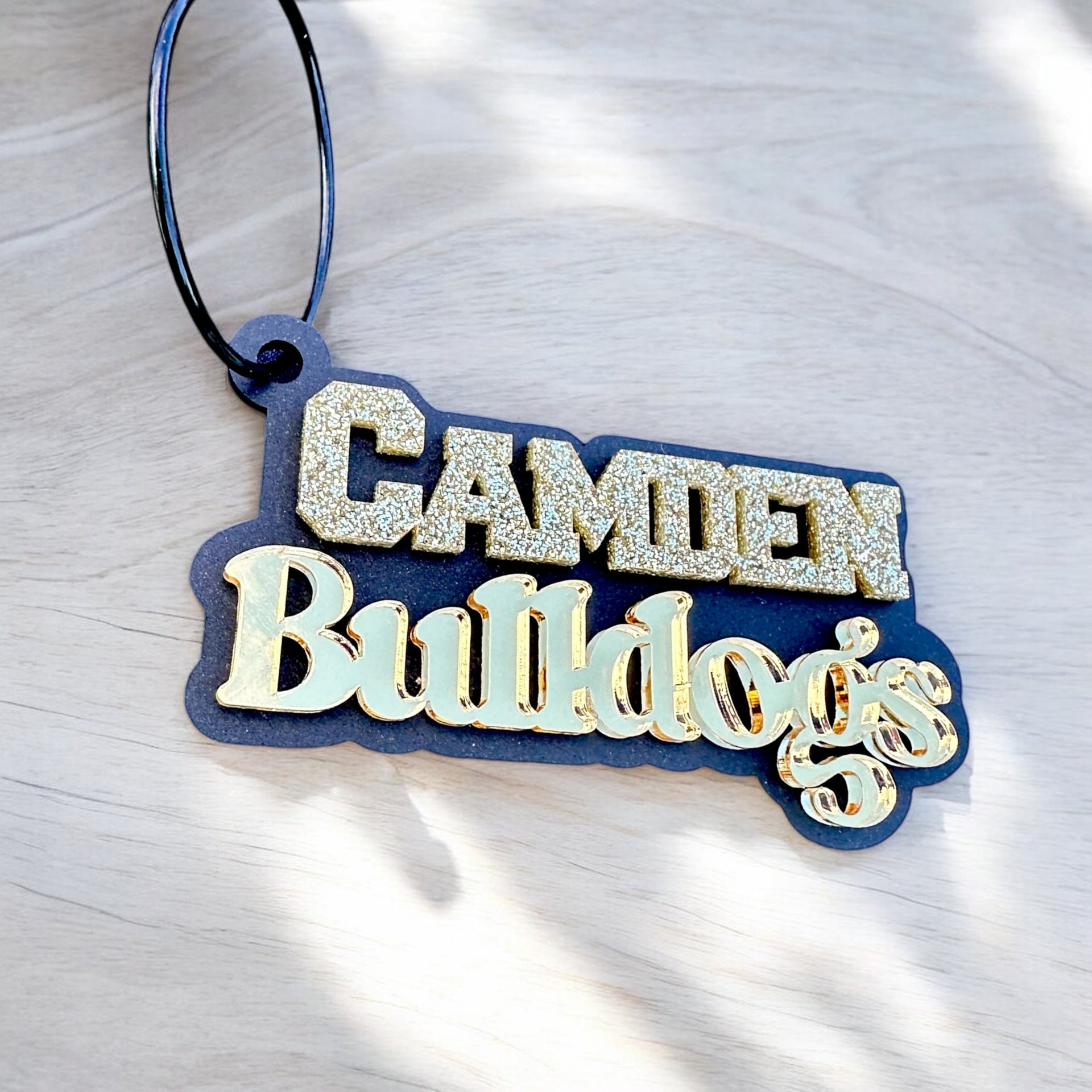 A keychain with the name "CAMDEN" and "Bulldogs" written on it in a decorative font.
