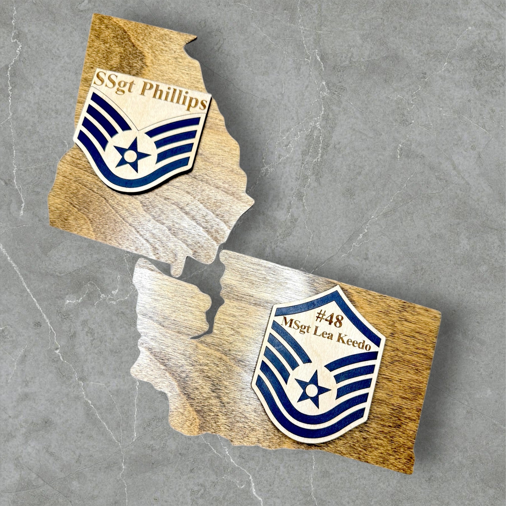 Wooden cutouts of a map of Ohio with engraved names and insignias on a wooden surface.