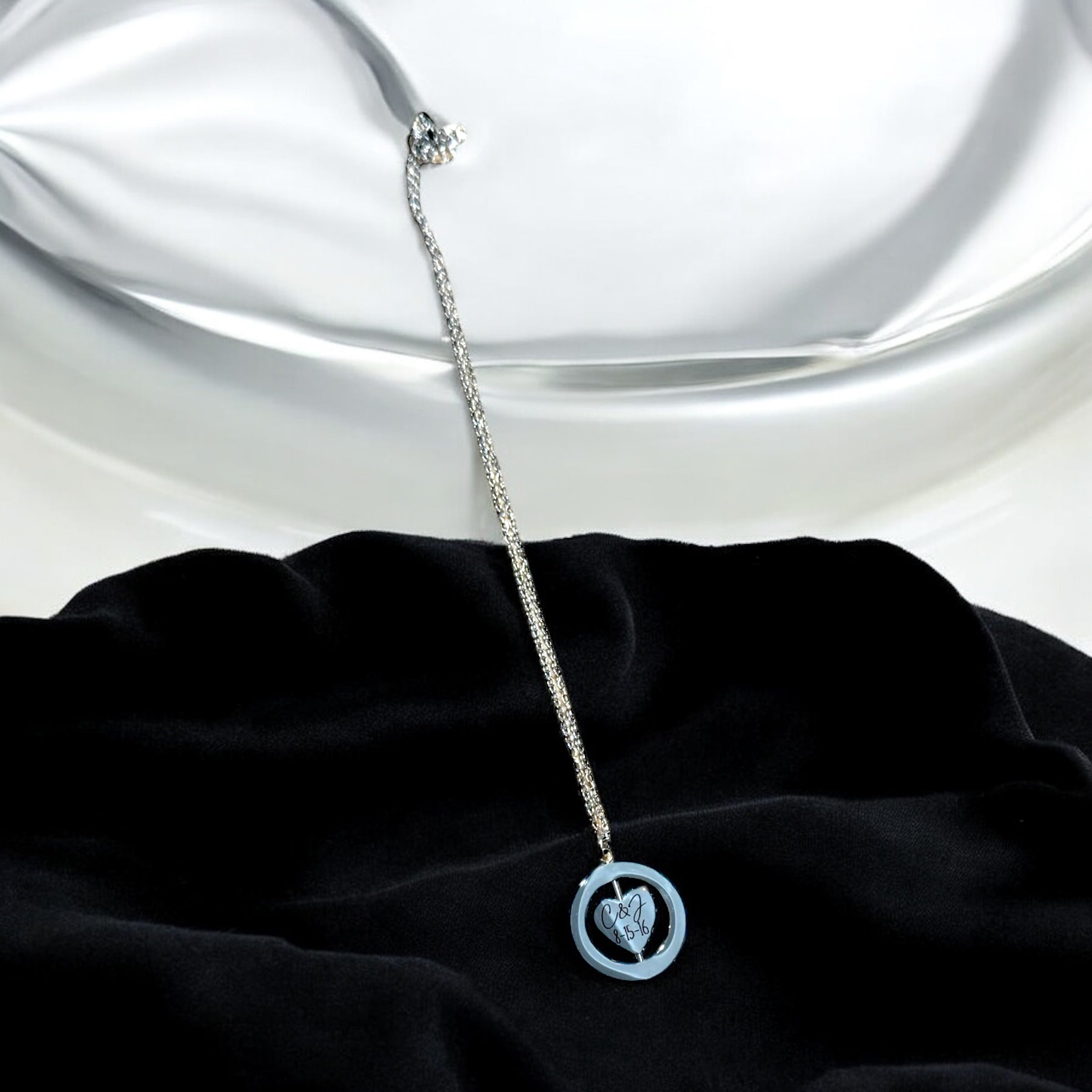 Silver necklace with a heart pendant on a black fabric background