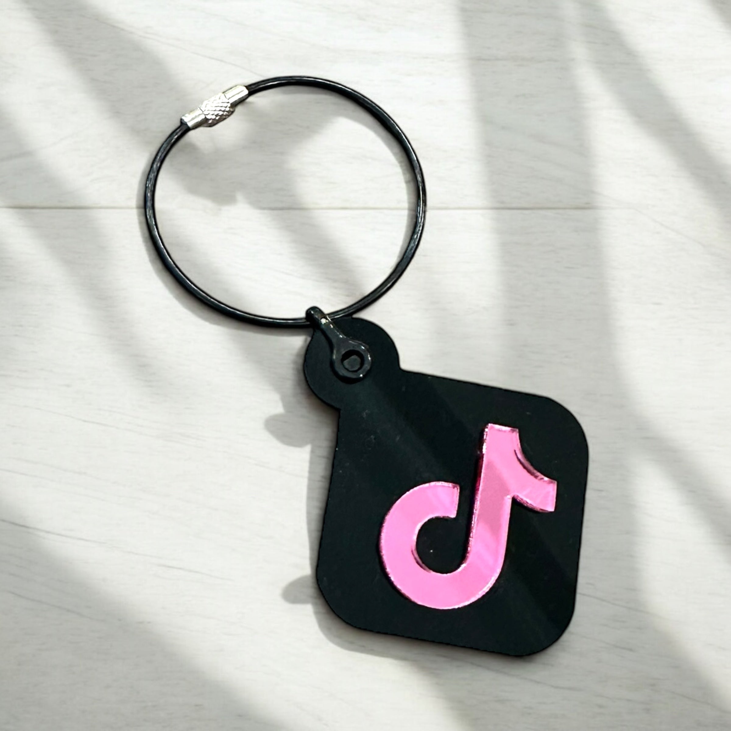 A black luggage tag with a pink "t" logo is shown on a white surface.