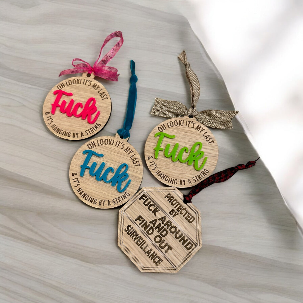 four wooden ornaments with the word "FUCK" written on them, along with a sign that reads "FUCK AROUND SURVEILLANCE".