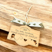 A wooden ornament with a ribbon and a message about the love between friends, hanging on a wooden surface.