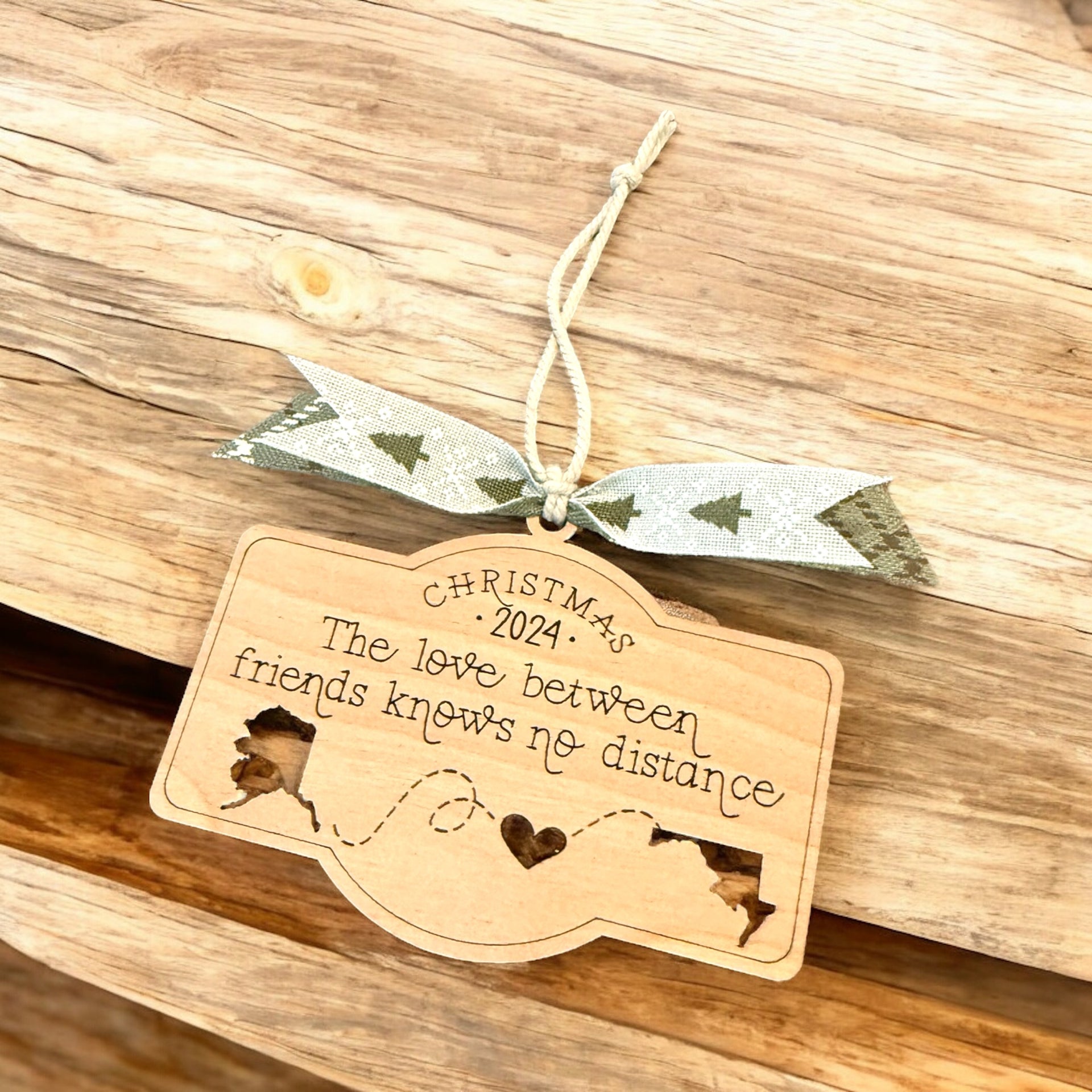 A wooden ornament with a ribbon and a message about the love between friends, hanging on a wooden surface.