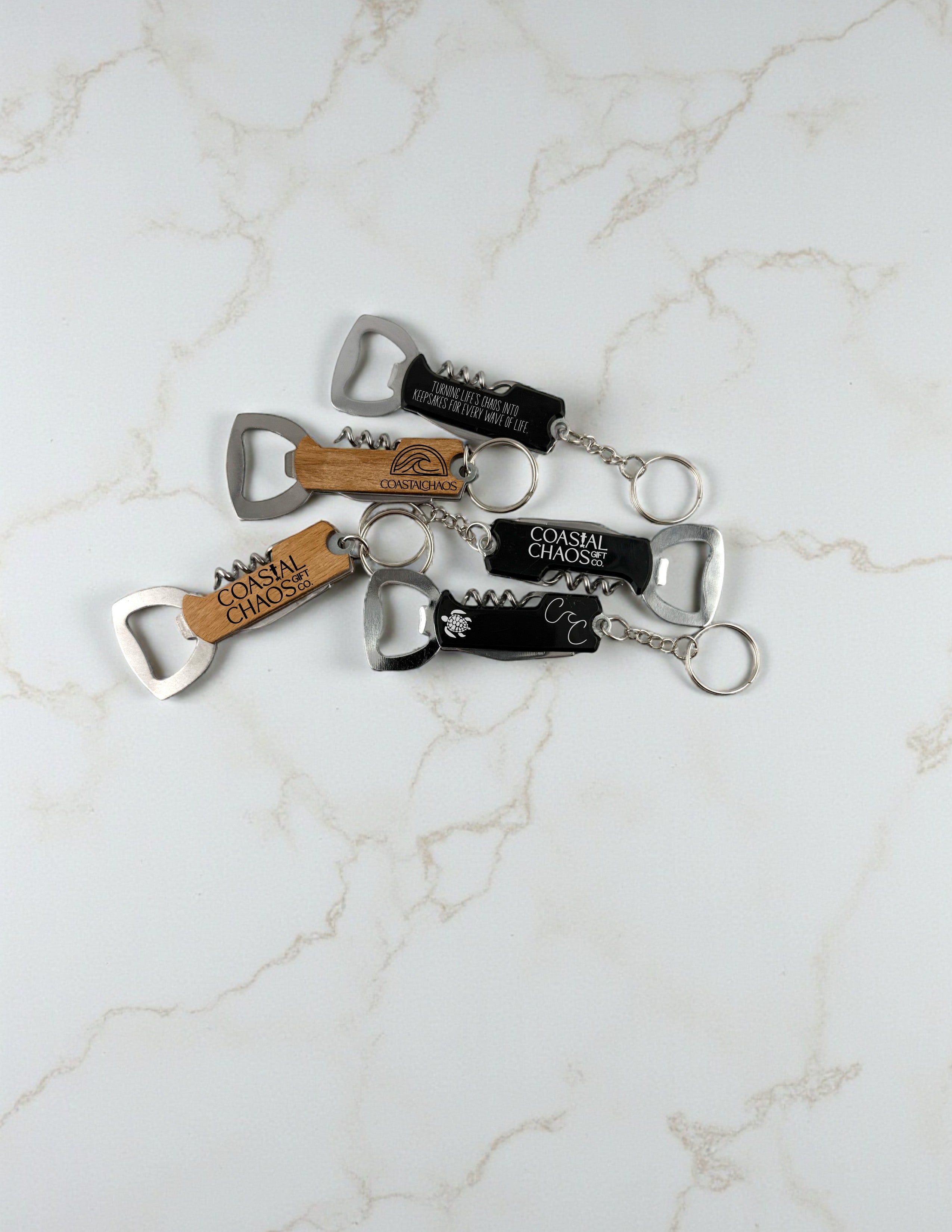 Coastal Chaos Co custom engraved corkscrew and bottle opener keychains in wood and black finishes.