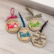 four wooden ornaments with various sayings on them, placed on a wooden surface.